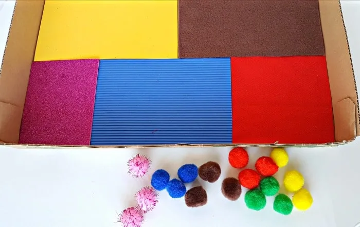 fabric scraps and pompoms sensory box for toddlers