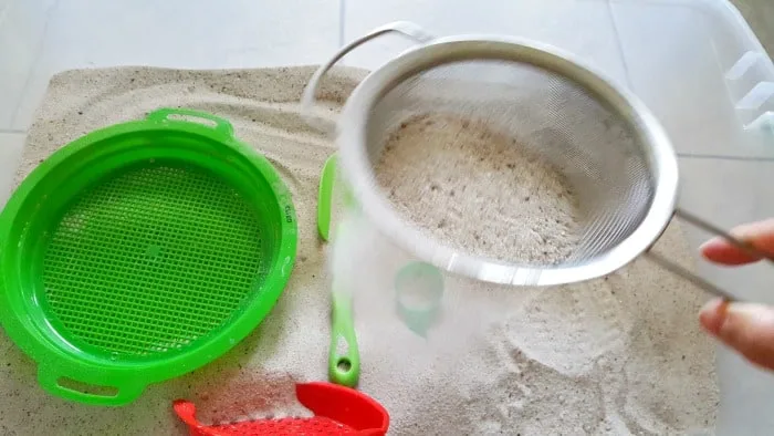 sifting sand through mesh strainer in sandbox play