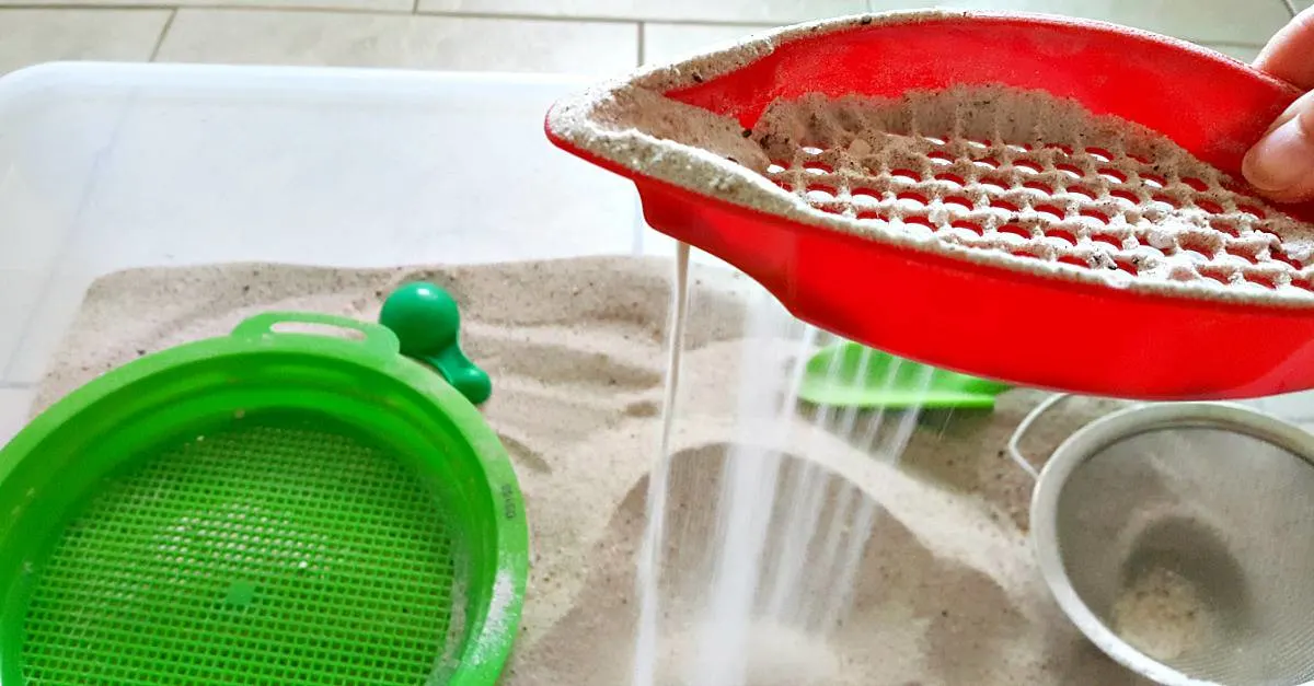 sifting sand through plastic strainer