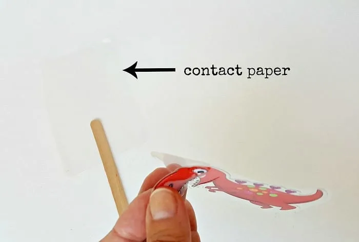 Remove sticker from adhesive backing to make craft stick puppet