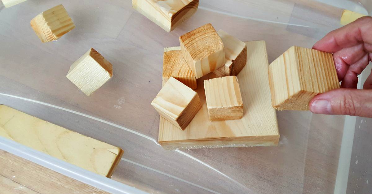 Stack small wood blocks in a water play activity for toddlers