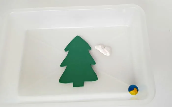 Place tree cutout in plastic bin with white paint and a marble for toddler painting activity