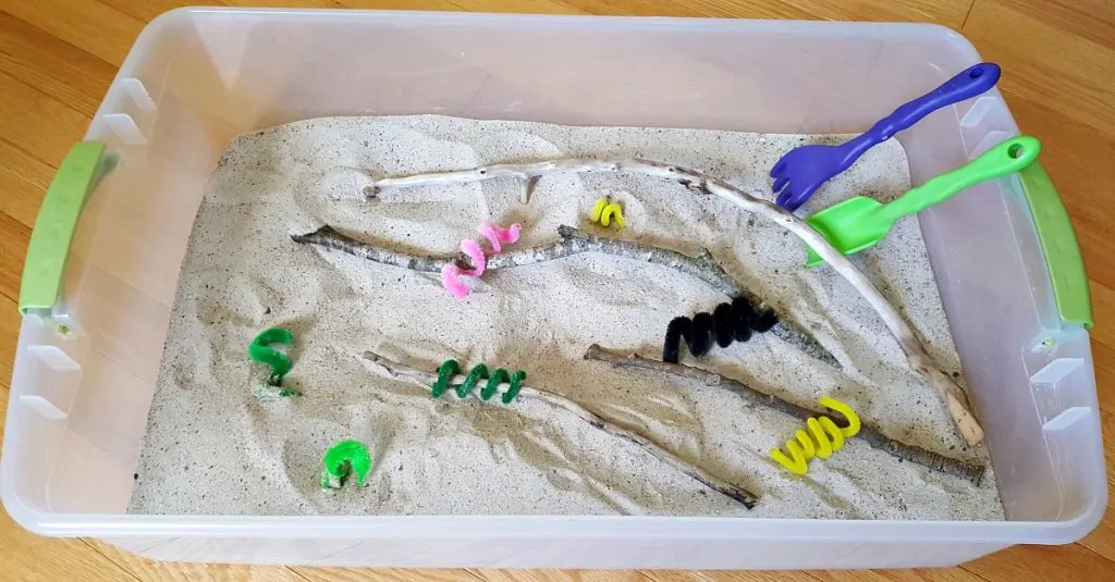 Sensory bin with chenille stem caterpillars and small branches