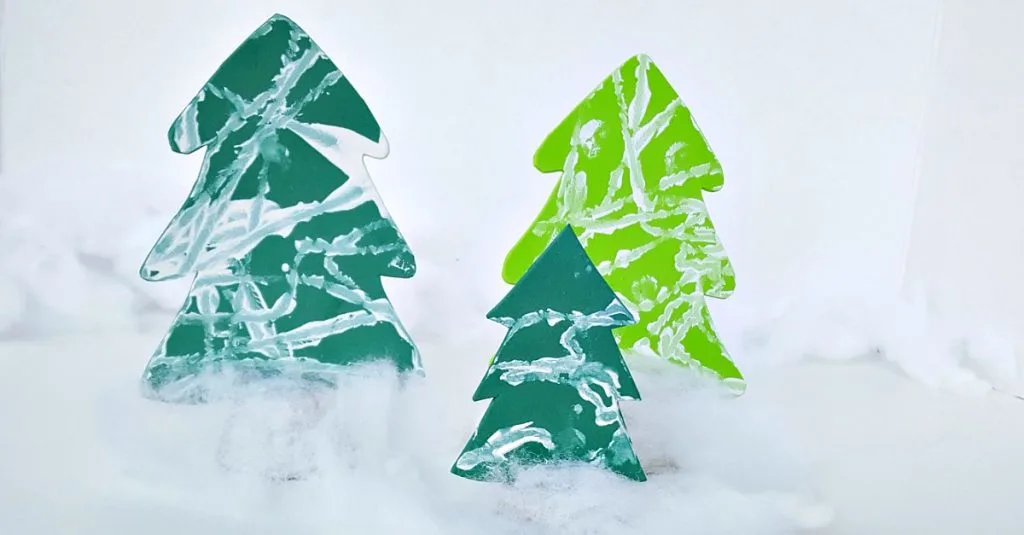 Toddler winter activity painting tree cutouts with a marble in white paint