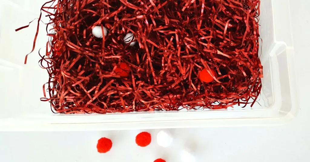 Toddler activity with tinsel and pompoms in the sensory bin