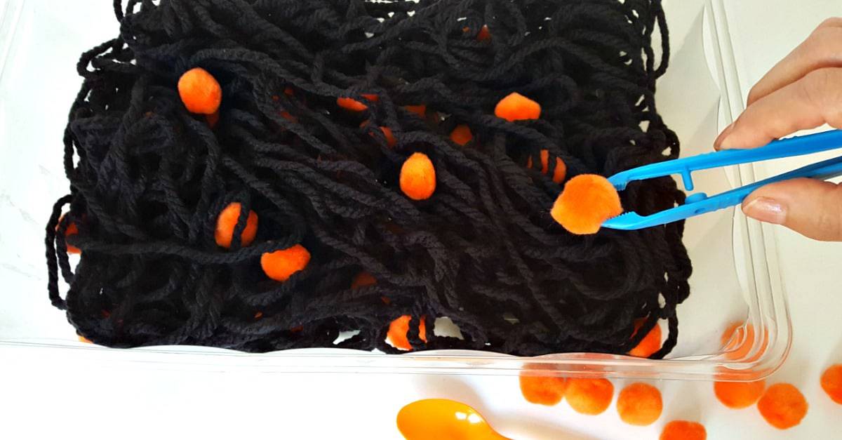 Use tongs in the sensory bin to pick up pompoms